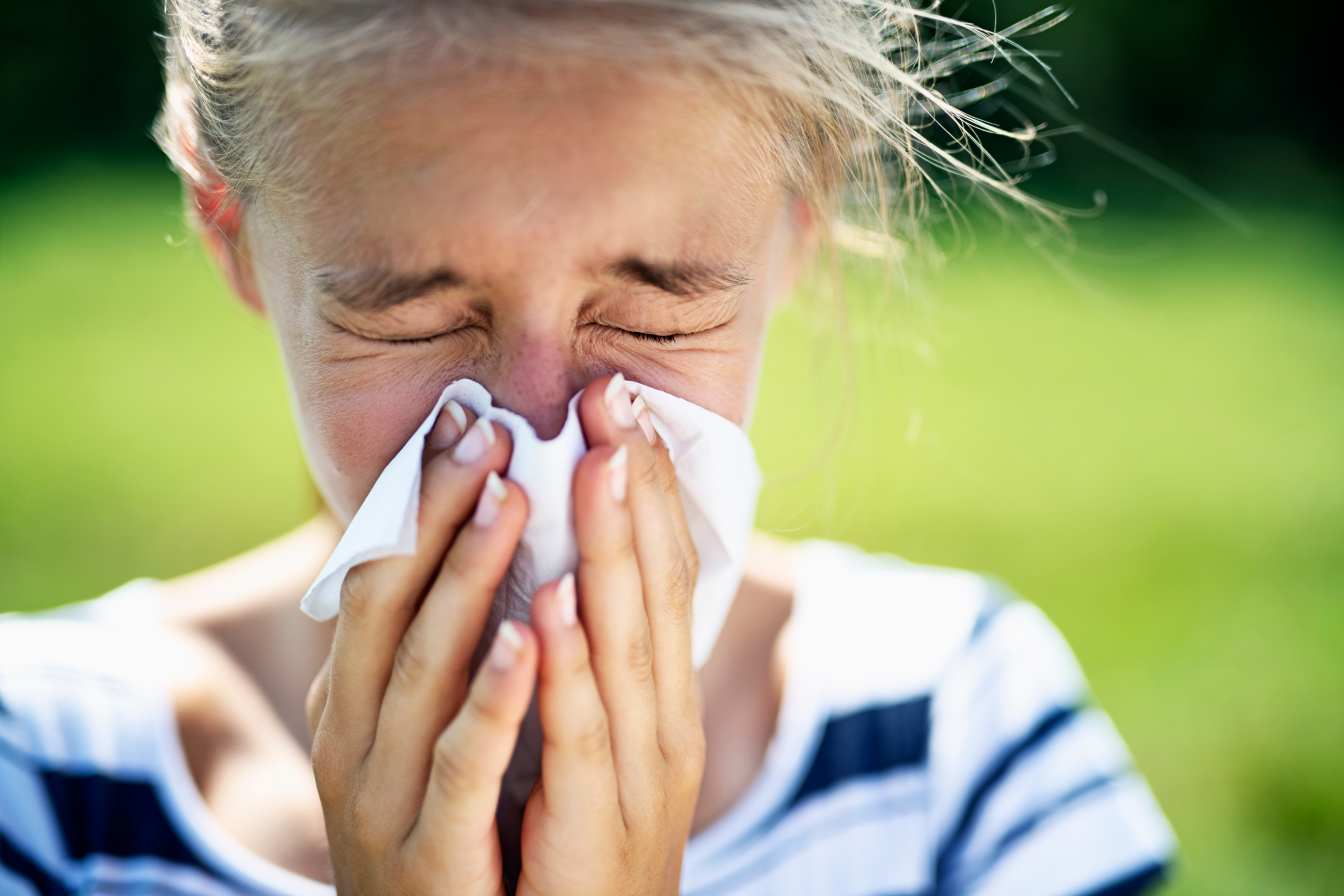 young girl blowing nose due to seasonal allergies