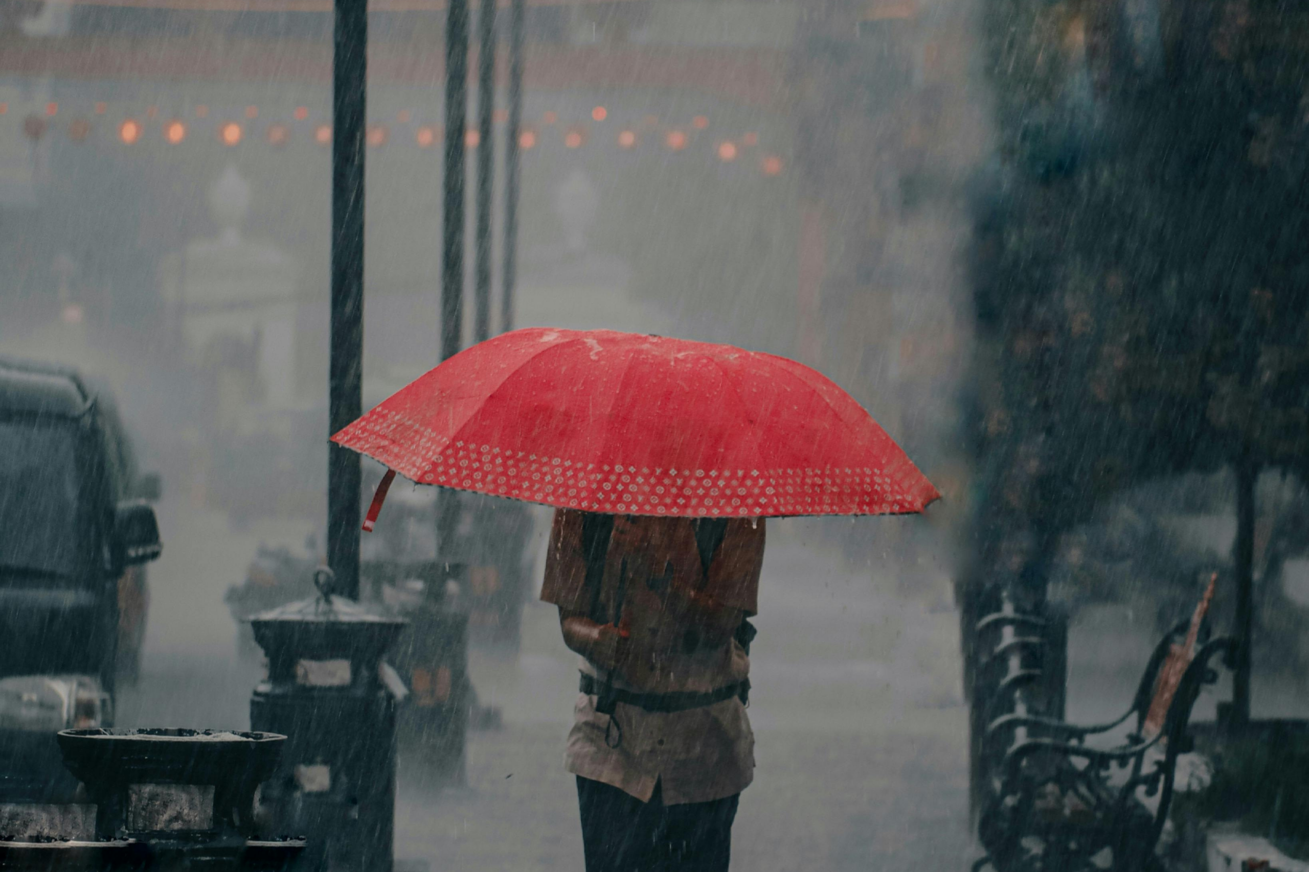 man with red umbrella in a rainstorm
